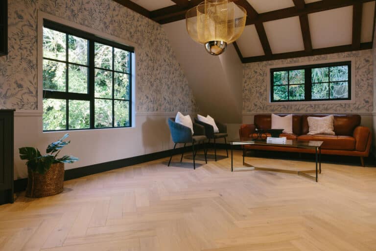 Sazerac Herringbone floor in a lounge with botanical wallpaper and black-framed windows
