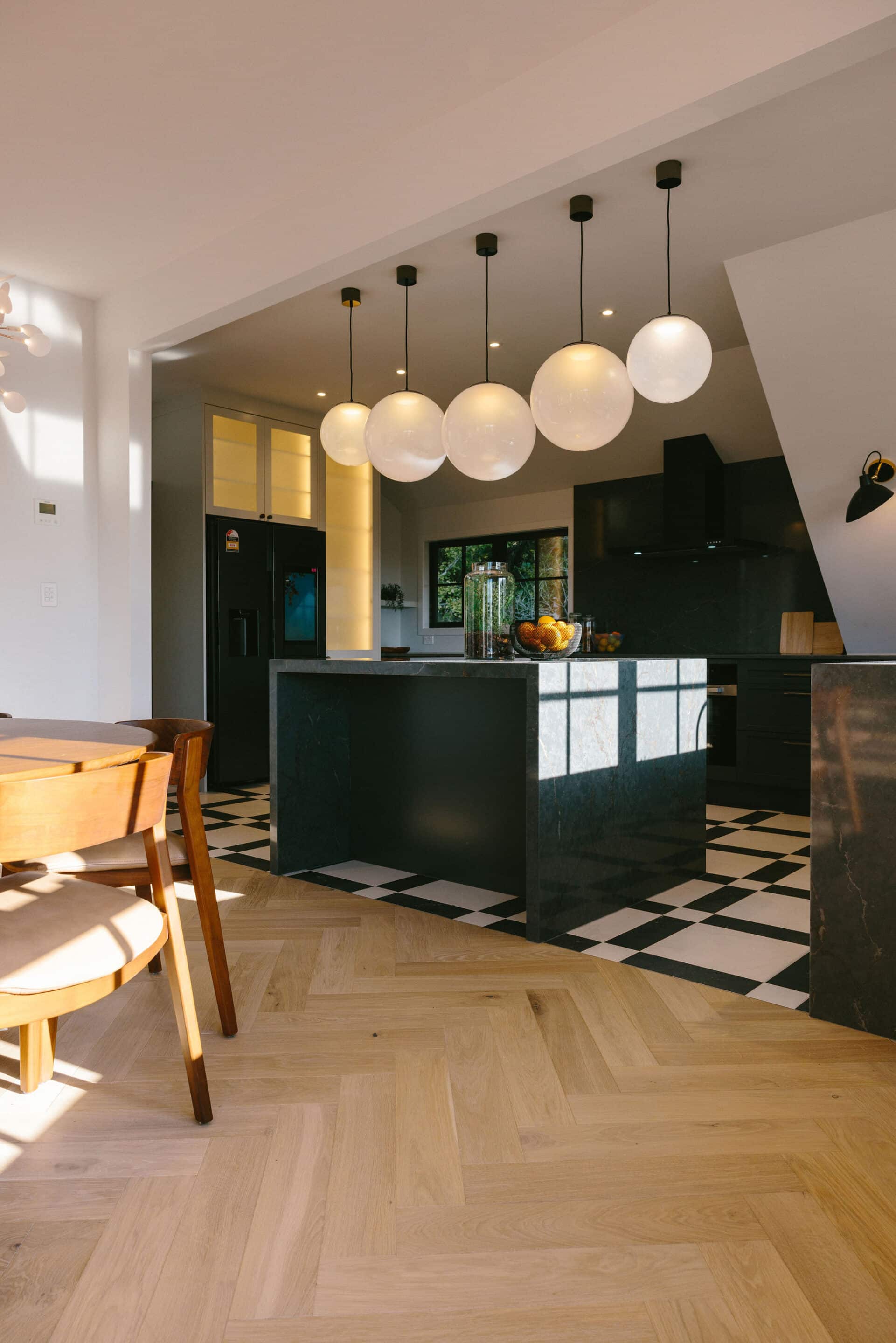 Kitchen with black joinery above herringbone European oak flooring