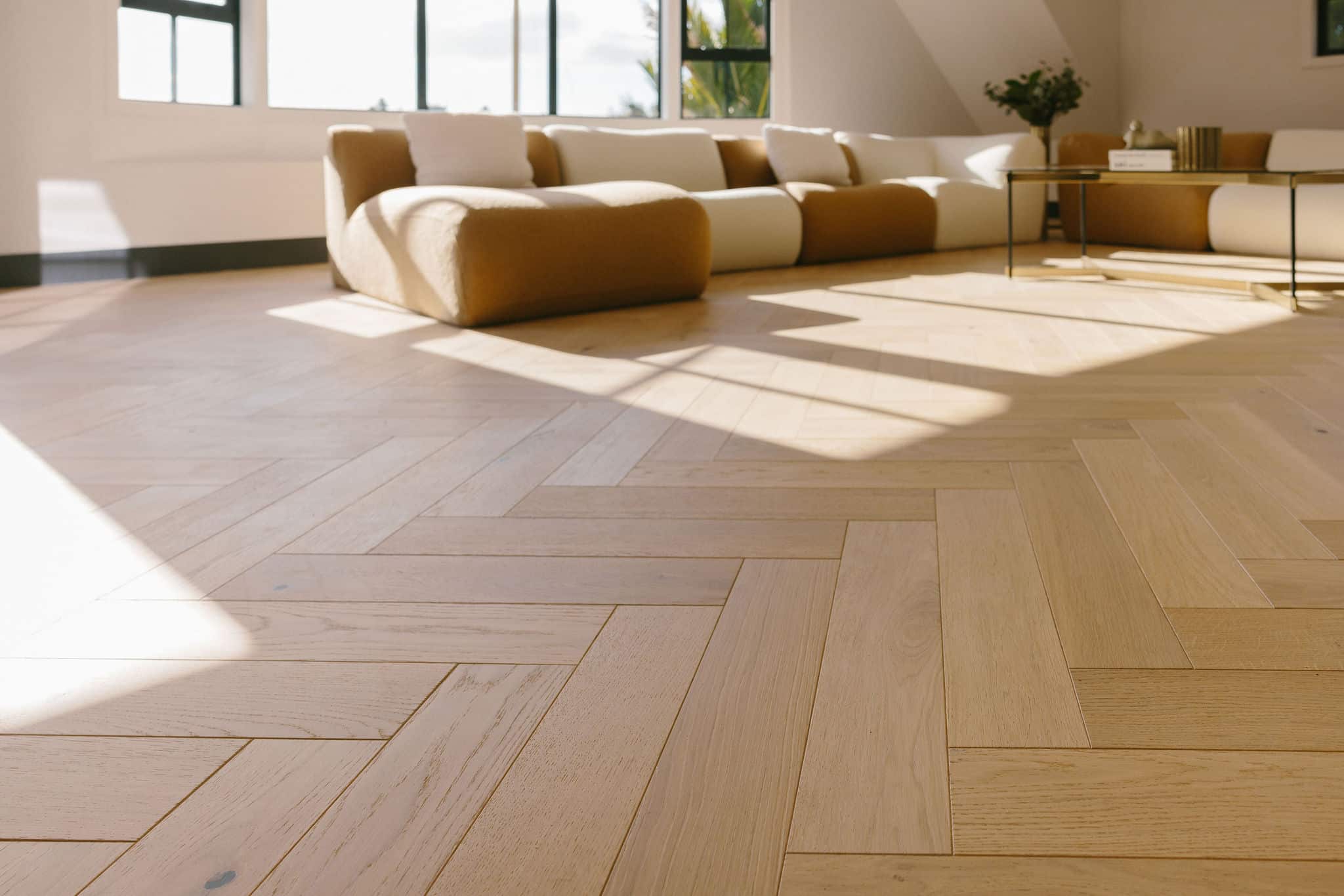 Herringbone oak parquet filling the frame in a light-filled lounge