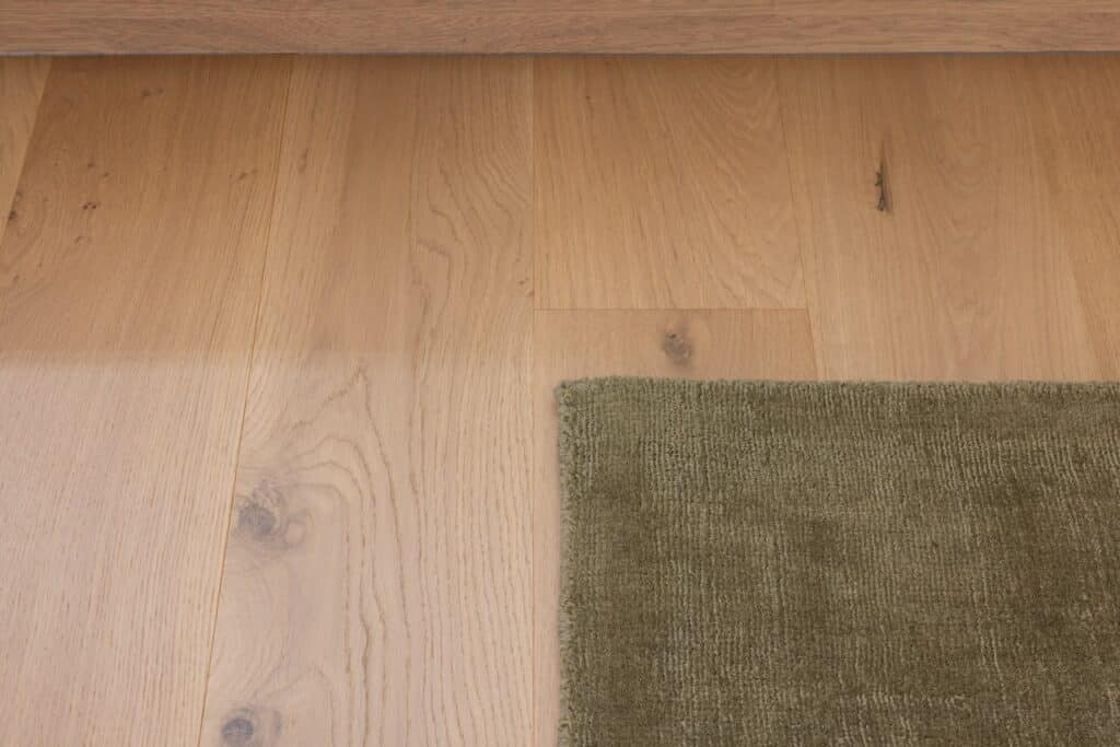 Close up of Bordeaux European oak timber flooring with green rug in Auckland home