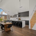 Wide plank European oak flooring in a modern kitchen with marble island, timber dining table and architectural loft staircase in a Queenstown New Zealand home