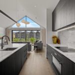 Wide plank European oak flooring in a modern kitchen and living room with marble island bench and large gable window bringing natural light into a Queenstown New Zealand home