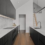 Wide plank European oak flooring in a modern kitchen with marble island bench, dark timber cabinetry and loft staircase in a Queenstown New Zealand home