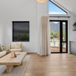 Wide plank European oak flooring in a modern living room with sofa, timber coffee table and mountain view through glazed doors in a Queenstown New Zealand home