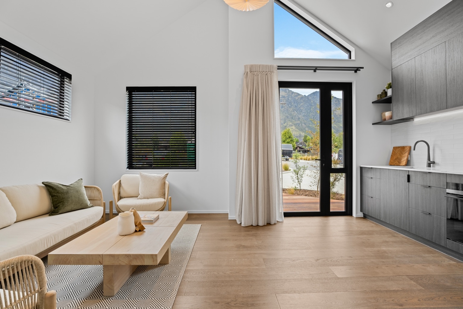 Wide plank European oak flooring in a modern living room with sofa, timber coffee table and mountain view through glazed doors in a Queenstown New Zealand home