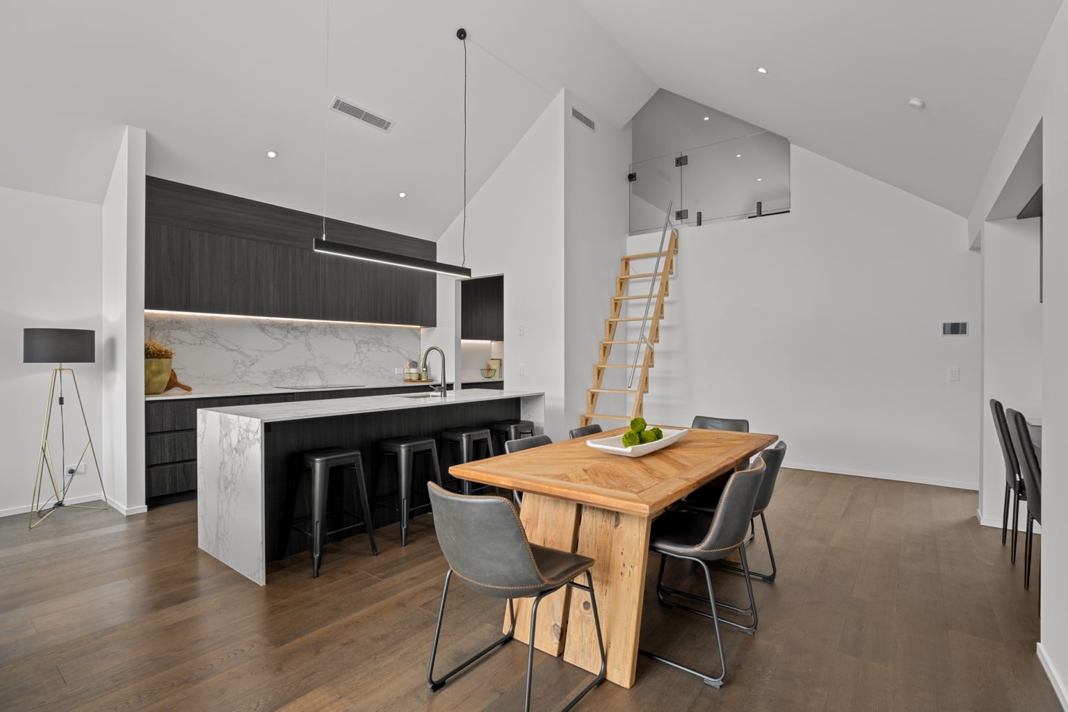 Wide plank European oak flooring in a modern kitchen and dining area with timber dining table and loft staircase in a Queenstown New Zealand home