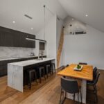 Wide plank European oak flooring in a modern kitchen and dining area with marble island, timber dining table and loft staircase in a Queenstown New Zealand home