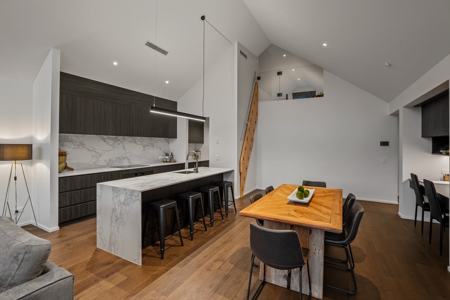 Wide plank European oak flooring in a modern kitchen and dining area with marble island, timber dining table and loft staircase in a Queenstown New Zealand home