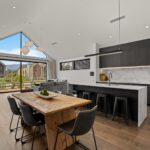 Wide plank European oak flooring in an open plan kitchen and living area with marble island, dining table and mountain view windows in a Queenstown New Zealand home
