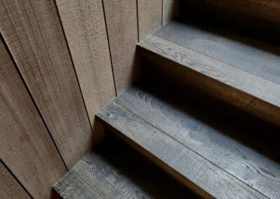 Dark engineered oak timber staircase with vertical timber wall lining and detailed stair treads