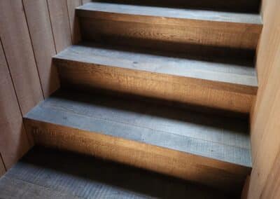 Engineered oak timber staircase transitioning from upper level with vertical timber wall detail