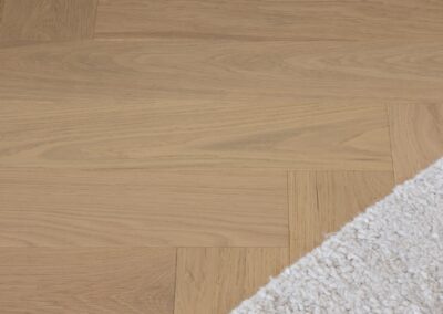 Edge of a rug over Bordeaux engineered oak herringbone flooring in Westmere home