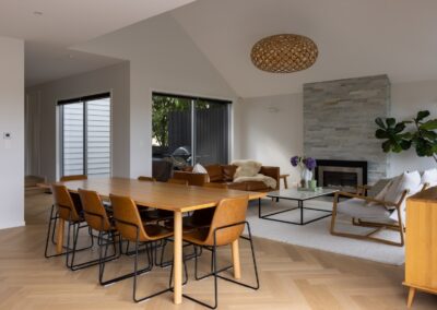 Dining room with fireplace over Bordeaux herringbone oak flooring in Westmere home