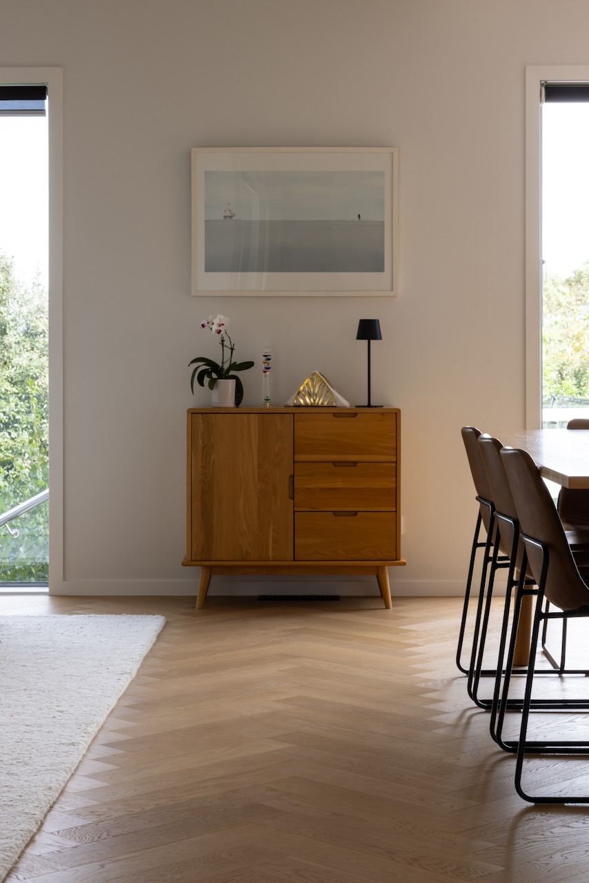 Dining area with timber sideboard over Bordeaux herringbone oak flooring in Westmere home