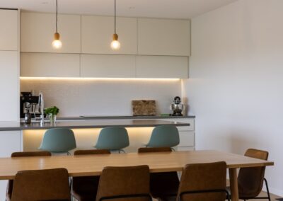 View from dining area into kitchen over Bordeaux herringbone oak flooring in Westmere home