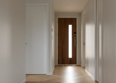 Entry hallway with front door and Bordeaux herringbone oak flooring in Westmere home