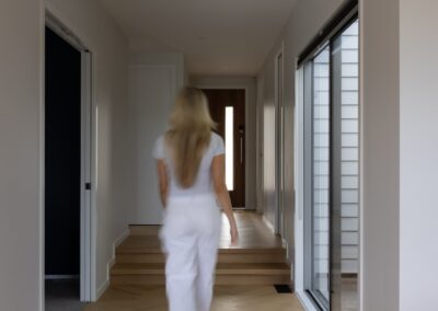 Lifestyle view of a person walking through hallway over Bordeaux herringbone oak flooring, Westmere home