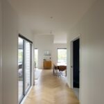 Hallway leading to dining area over Bordeaux herringbone oak flooring in Westmere home