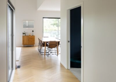 Hallway view with Bordeaux herringbone oak flooring flowing into dining area, Westmere home