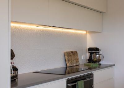 Kitchen cooktop and cabinetry above Bordeaux herringbone oak flooring in Westmere home