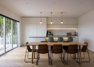 Kitchen and dining area with sliding door to outdoors over Bordeaux herringbone oak flooring, Westmere home
