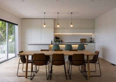 Kitchen and dining table with bar stools over Bordeaux herringbone oak flooring in Westmere home