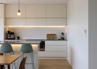 View from dining looking back to kitchen over Bordeaux herringbone oak flooring in Westmere home