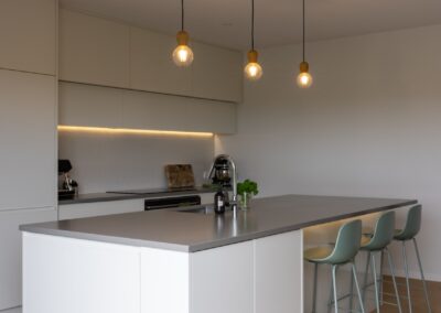 Kitchen island with bar stools over Bordeaux herringbone oak flooring in Westmere home