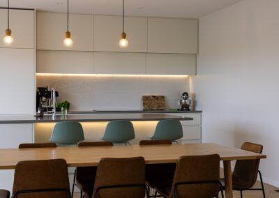 Close view of kitchen island and dining table over Bordeaux herringbone oak flooring, Westmere home