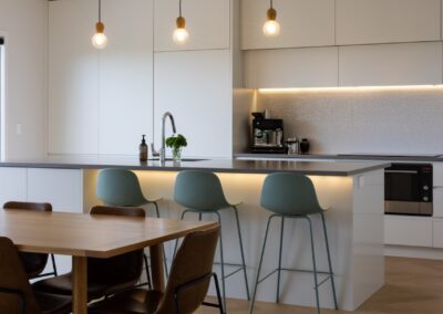 Kitchen island and dining zone with pendant lighting over Bordeaux herringbone oak flooring in Westmere home