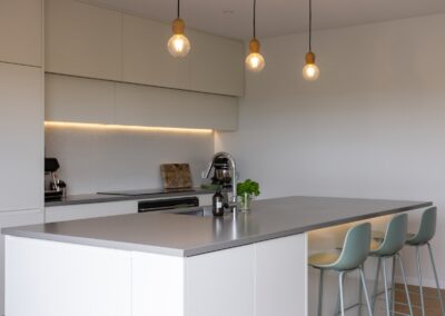 Kitchen island with pendant lights over Bordeaux herringbone oak flooring in Westmere home