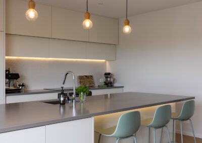 Kitchen island with sink over Bordeaux herringbone oak flooring in Westmere home