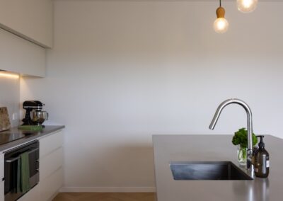 Kitchen sink and island over Bordeaux herringbone oak flooring in Westmere home