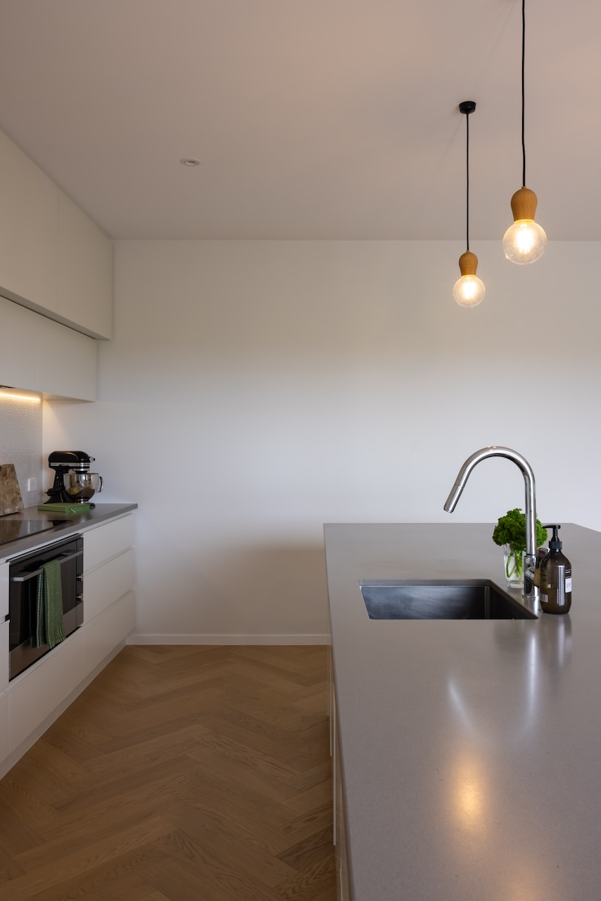 Kitchen sink and island over Bordeaux herringbone oak flooring in Westmere home