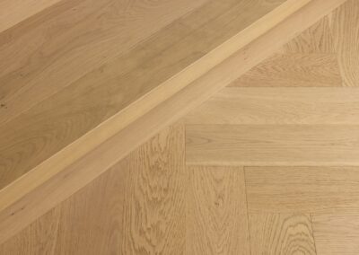 Bordeaux herringbone oak flooring meeting stair nosing detail in Westmere home