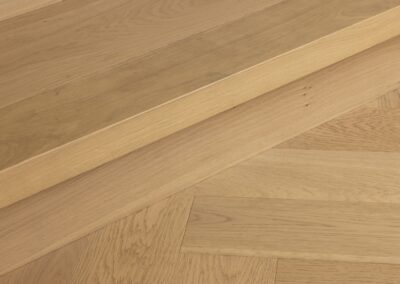 Bordeaux oak herringbone flooring meeting timber stair step detail in Westmere home