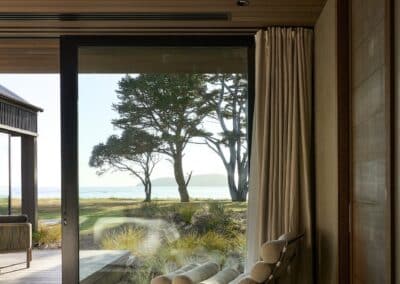 Dark engineered oak timber flooring in bedroom with floor to ceiling glass doors and coastal sea view