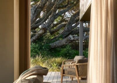 Dark engineered oak timber flooring transitioning from interior bedroom to outdoor deck with sliding doors and coastal setting