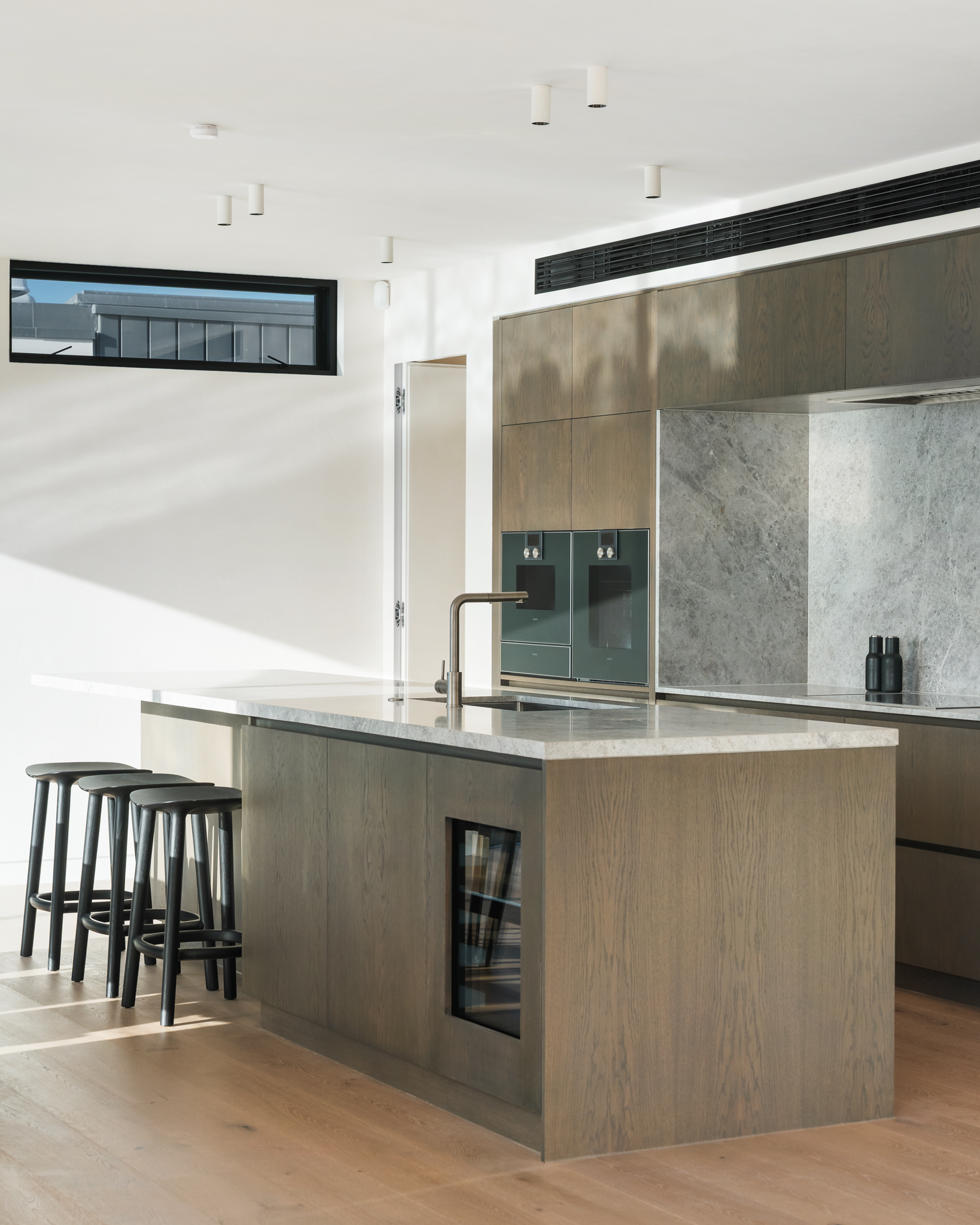 Westwood engineered oak flooring beneath a marble kitchen island, Westmere Auckland home.