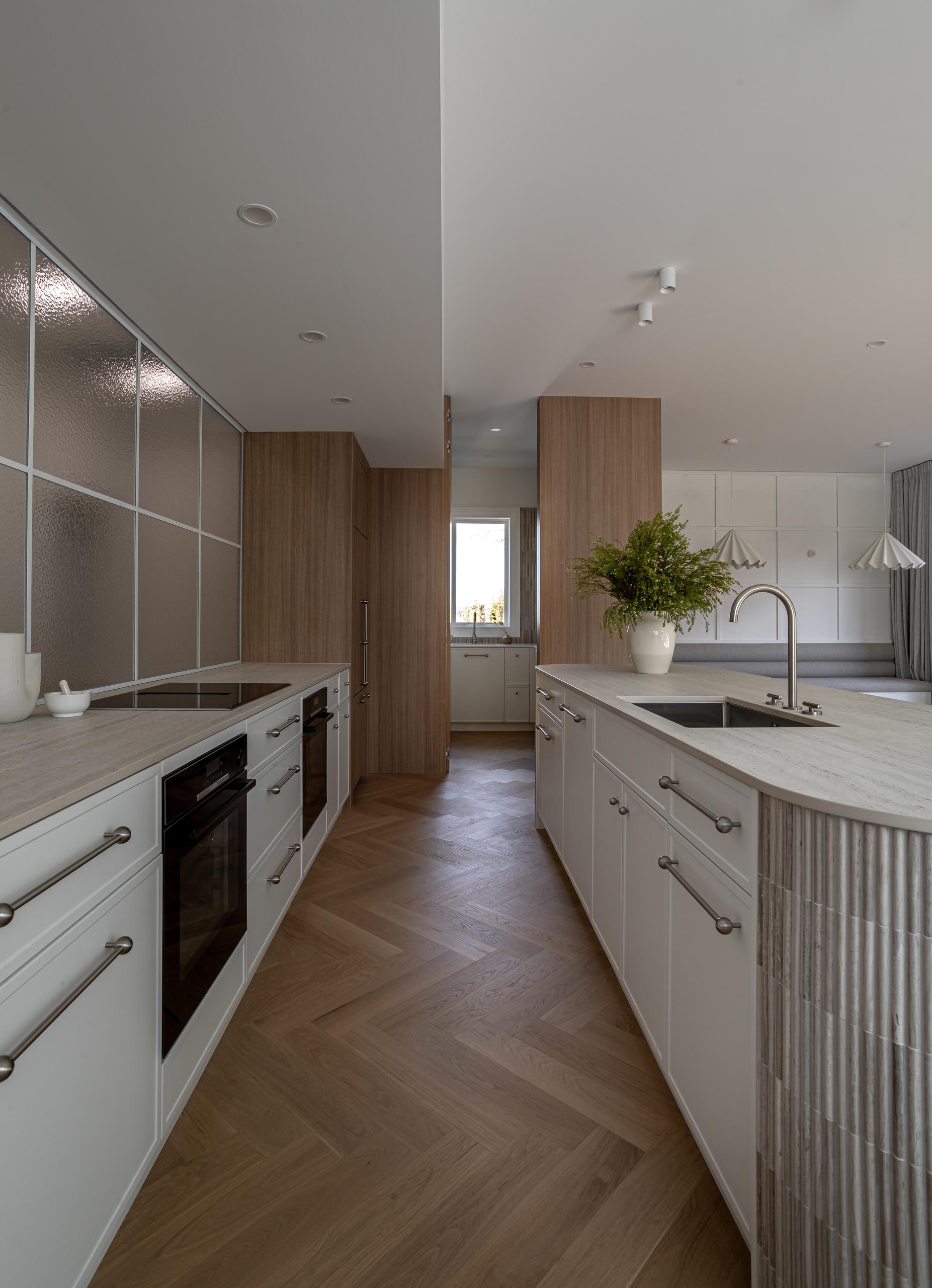 Bordeaux Herringbone oak parquet in a working Ponsonby kitchen with a stone island and integrated joinery.