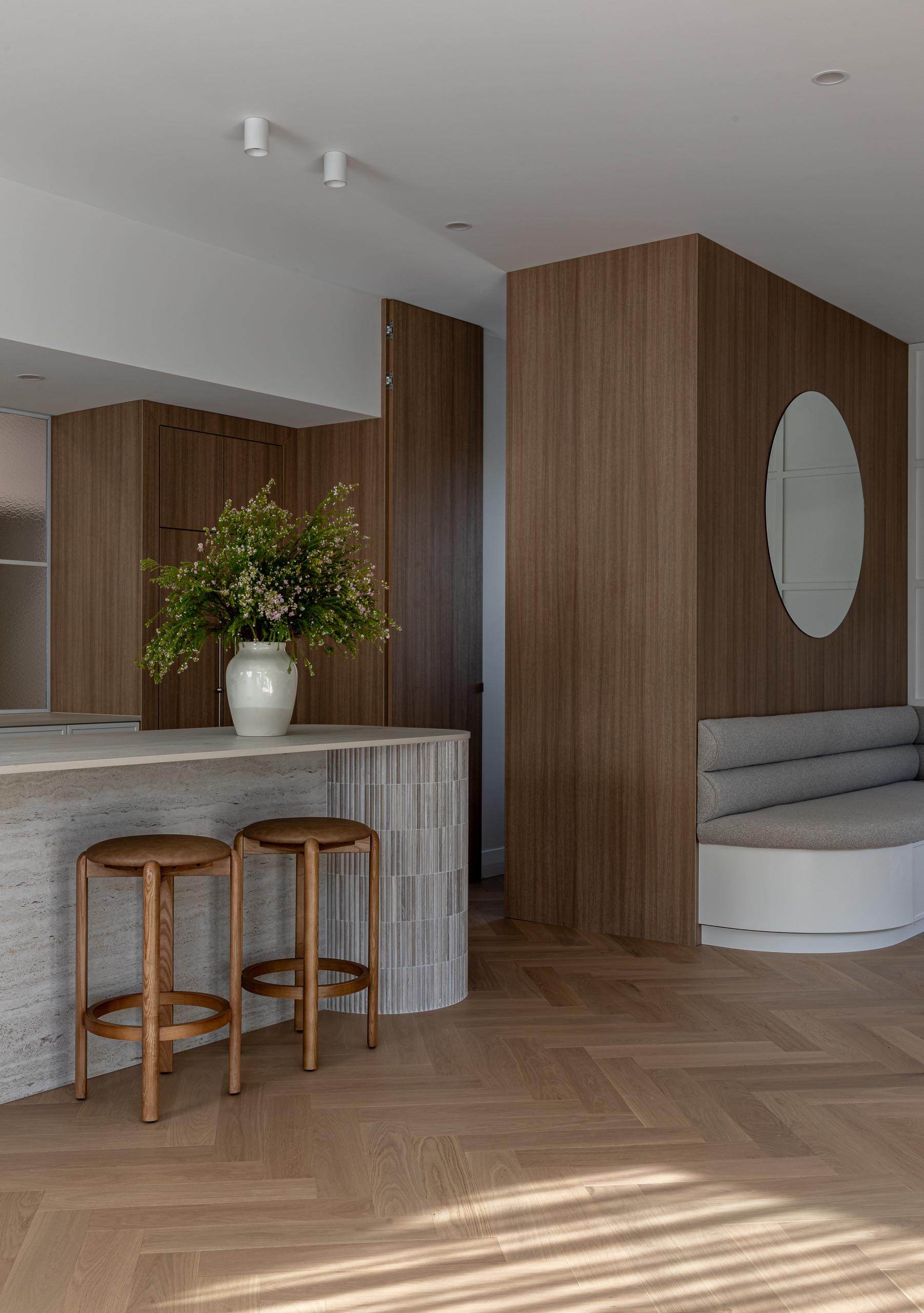 Open-plan living room with a fluted island and warm oak joinery above Bordeaux Herringbone parquet in Ponsonby.