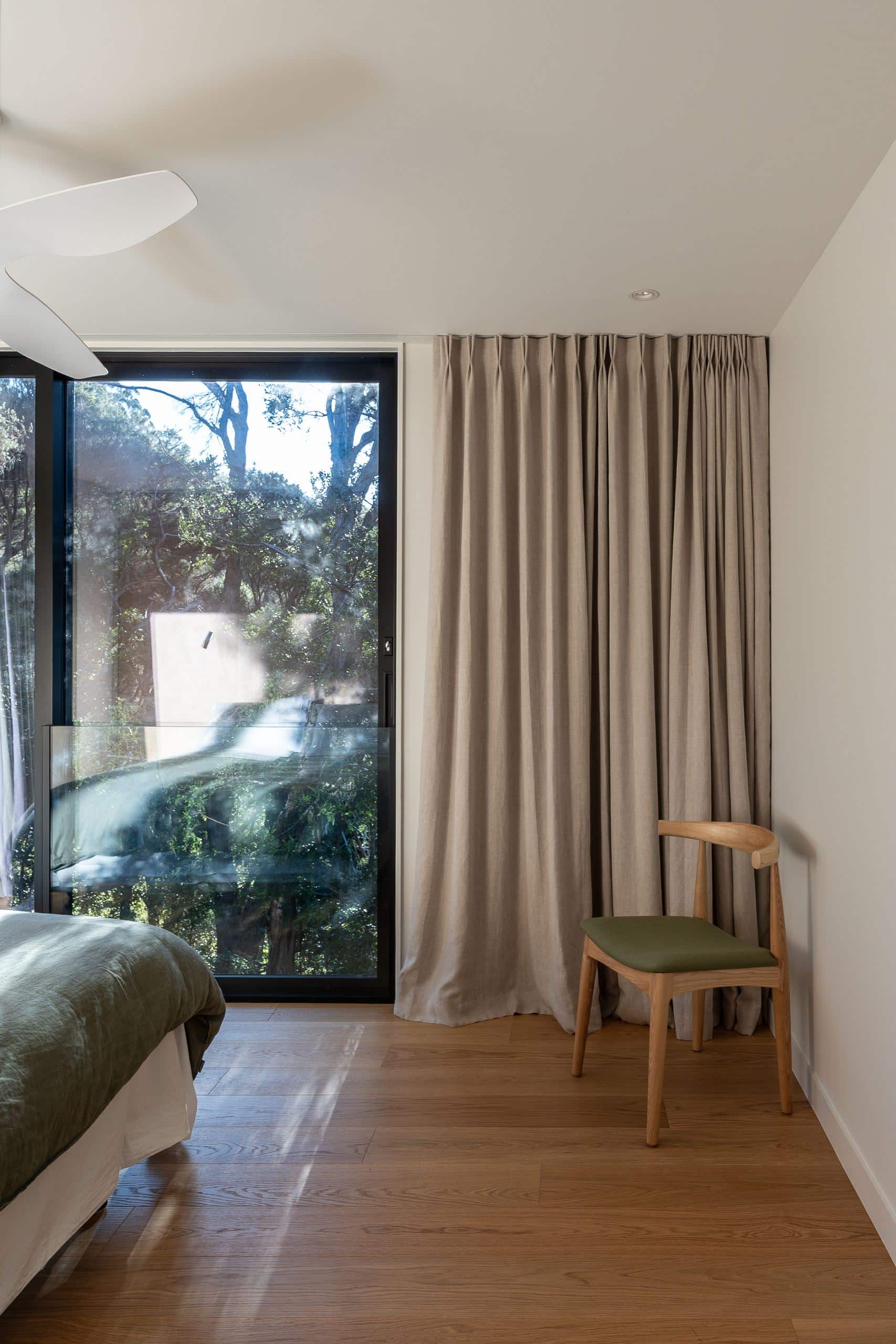 Foundation Pureline oak flooring in a Waiheke Island bedroom with linen curtains and a bush outlook.