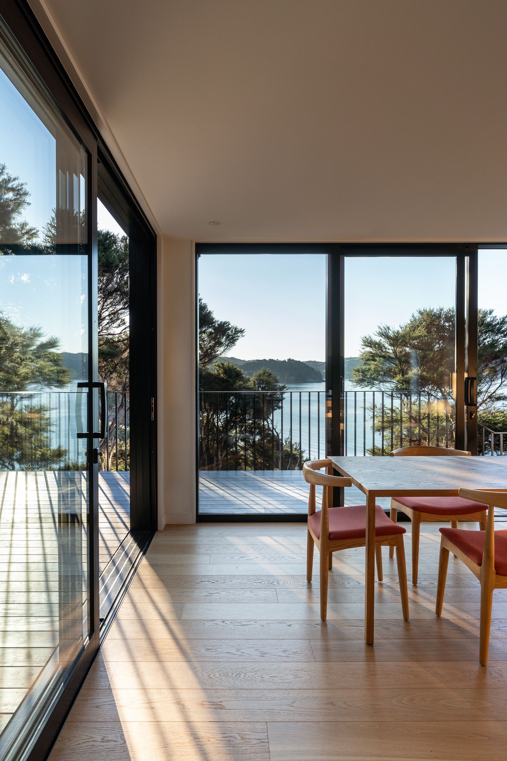 Foundation Pureline oak flooring beside sliding doors onto a deck, looking out to the sea from a Waiheke Island home.