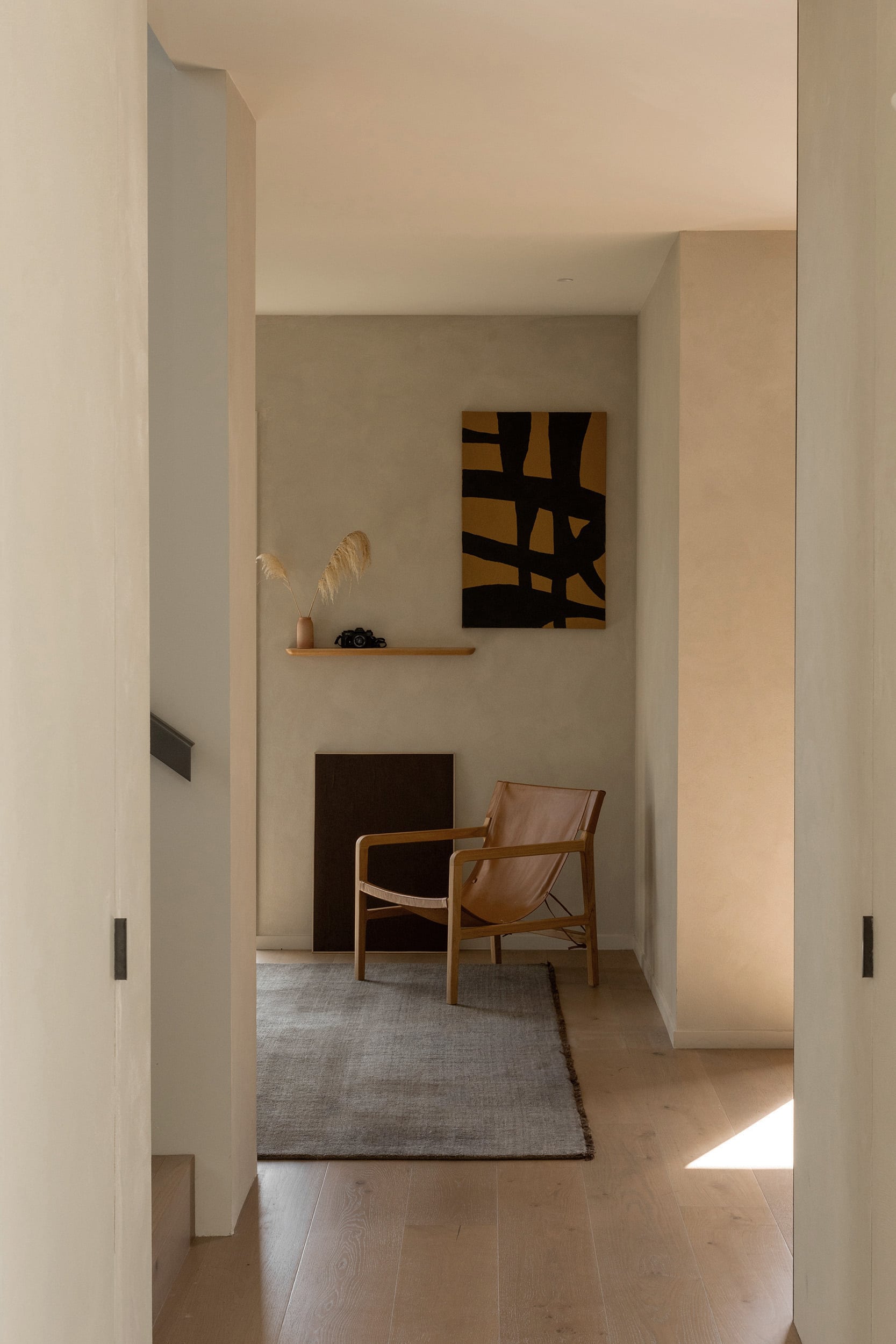 Icons Conde oak flooring running down a hallway to a reading nook with a leather sling chair and a rug.