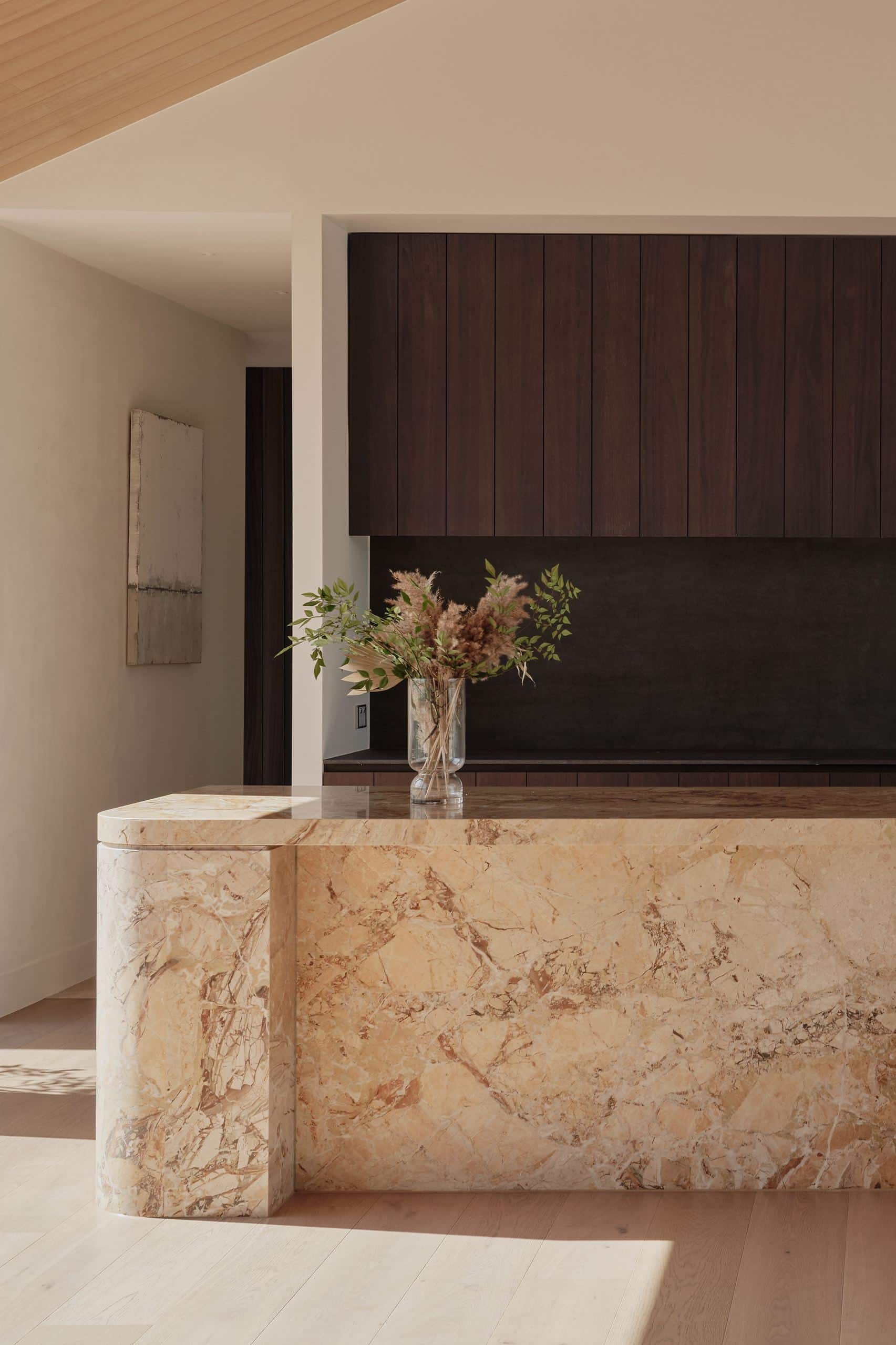 Icons Conde oak flooring in a Taupaki kitchen, beside a veined stone island and dark timber cabinetry.