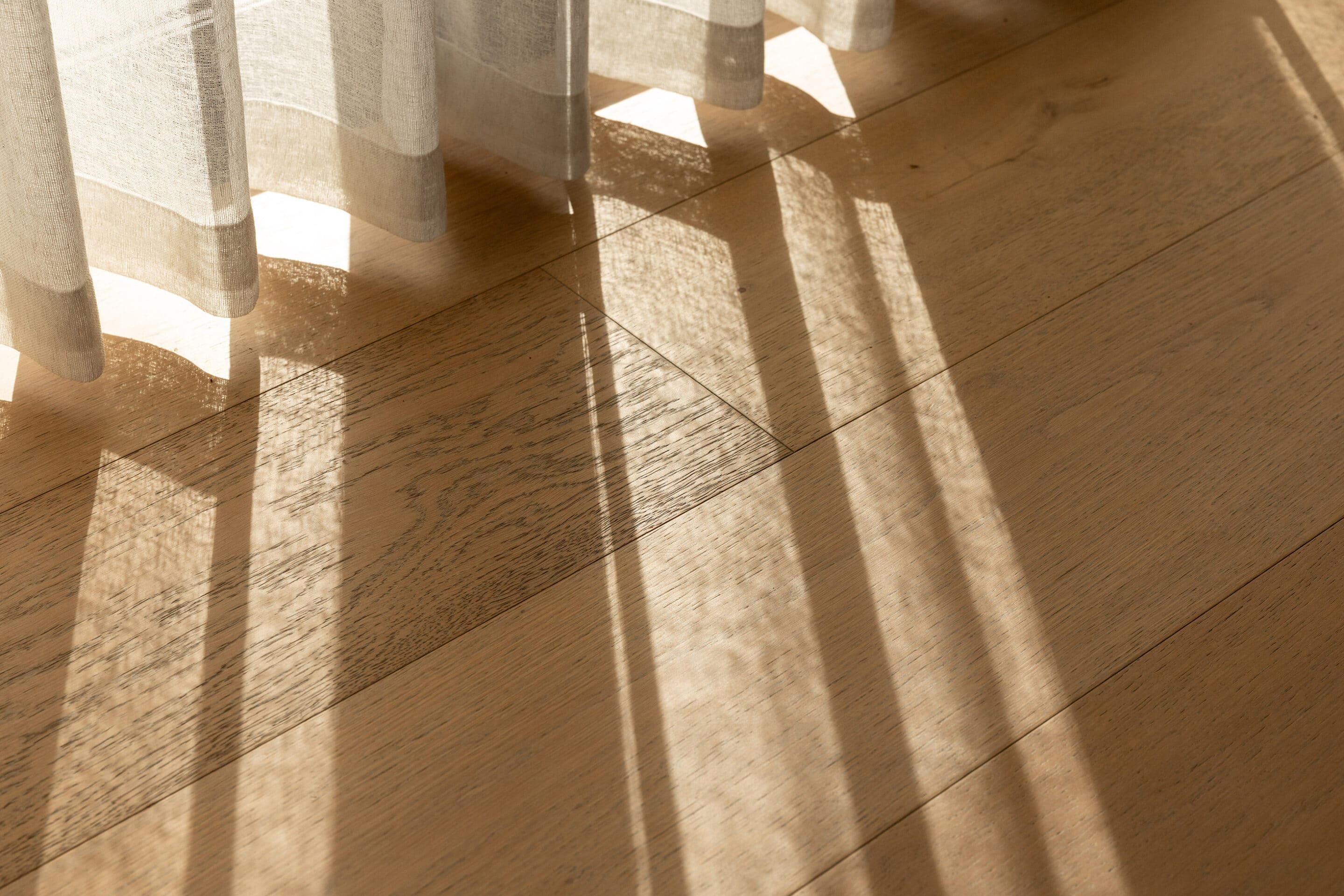 Close view of Icons Conde oak boards in raking sunlight, showing the grain and the wide plank joints.