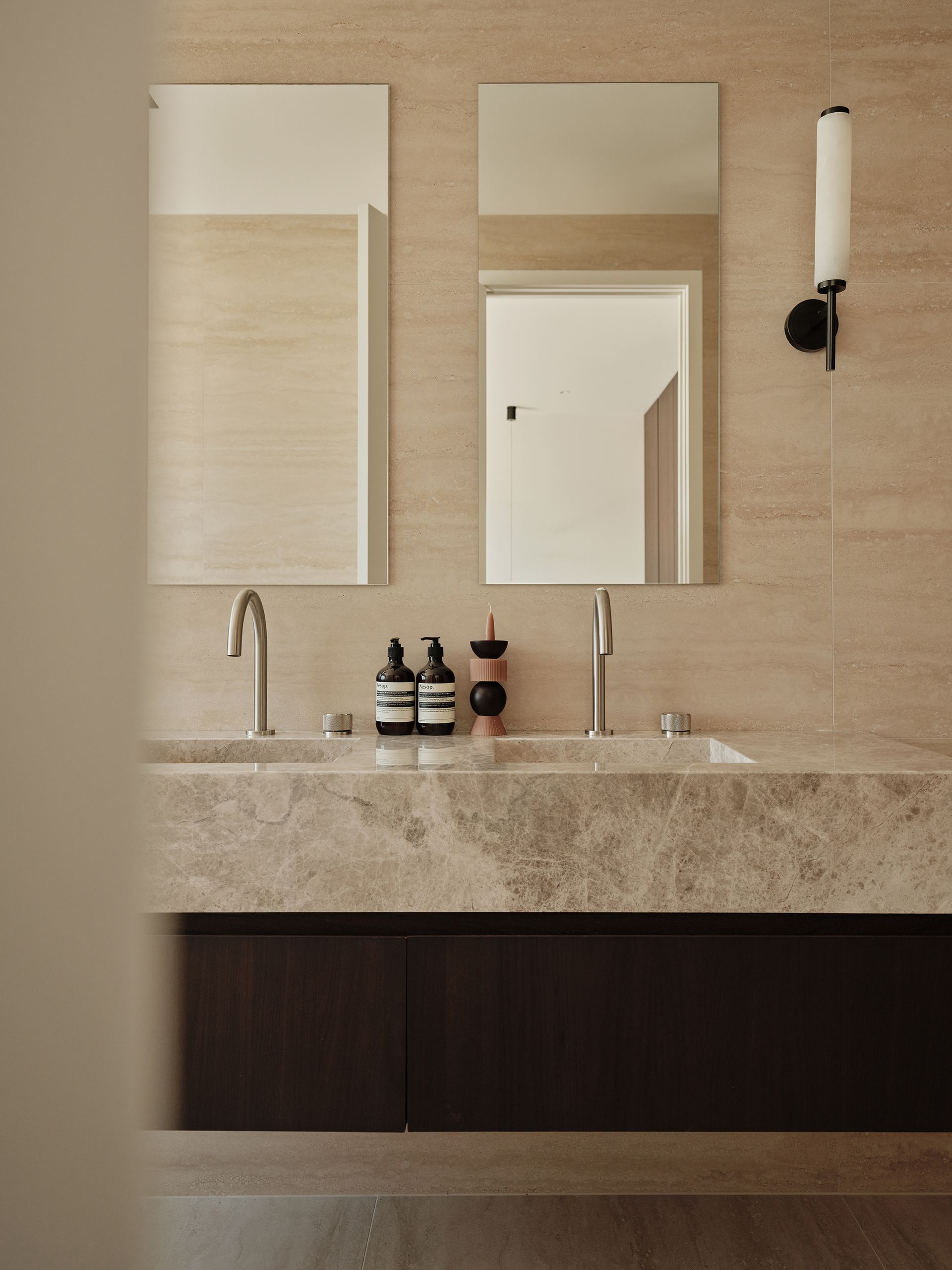 A stone double vanity against travertine-tiled walls in a Taupaki home bathroom.